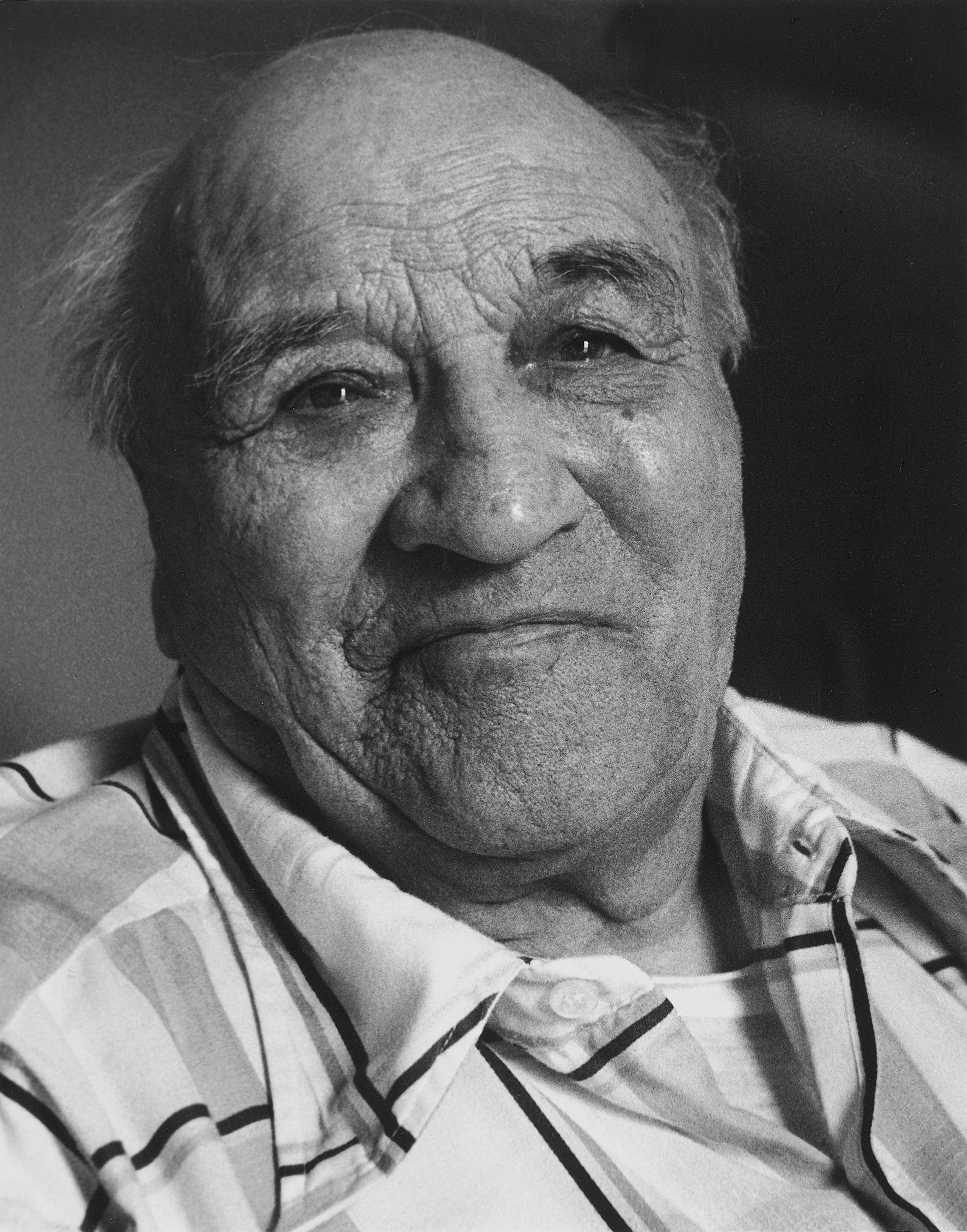 Black and white close-up photo of elderly man with strong, round shaped face.